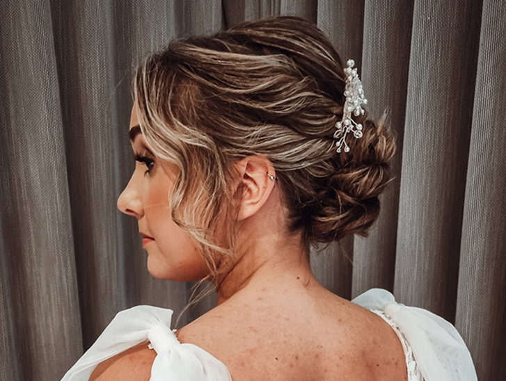 View of brides wavy updo with accessory from back